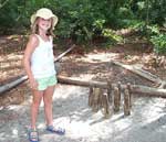 Sarah with the wooden bowling ball in hand and next to the wooden pins at the camp near the Elizabeth II.